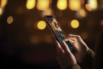 A woman smiling by bright slot machines showing lucky symbols, showcasing the exciting slot offerings at JL66.